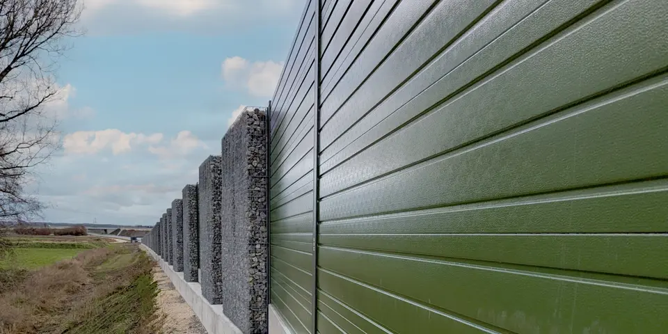 Gesamtansicht neu errichteter Lärmschutzwände in den Donauauen entlang der Querspange Erbach, mit farbigen Aluminiumelementen und Gabionen